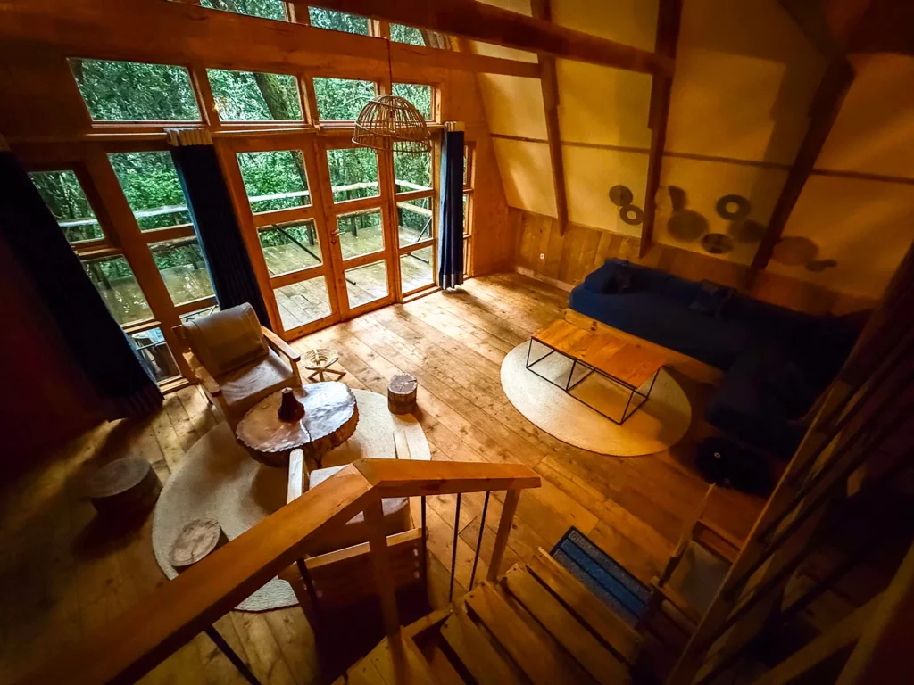 Wooden lounge area with sofa and coffee table viewed from loft at Munazi Lodge in Nyungwe National Park, Rwanda