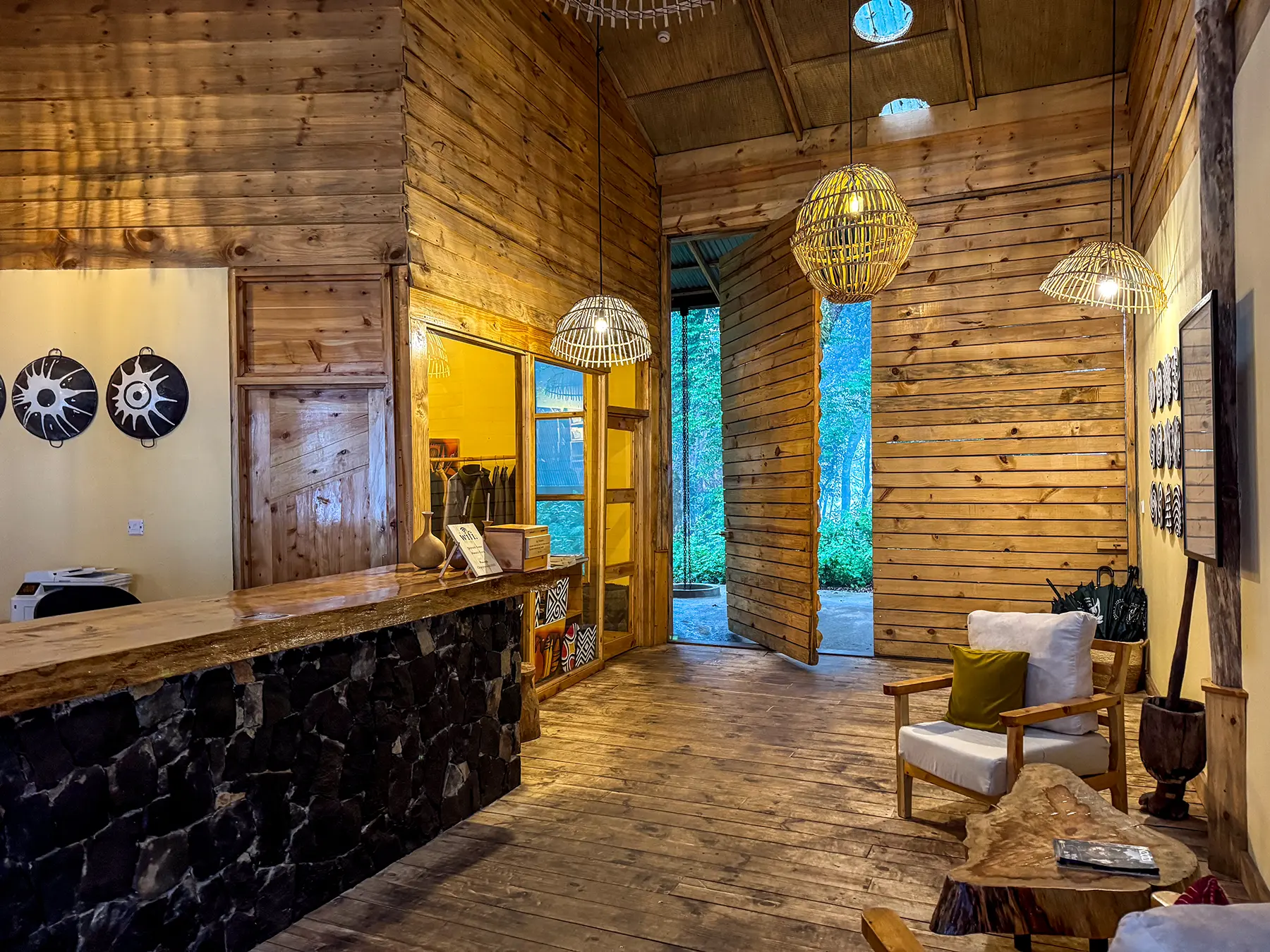 Timber reception area with woven pendant lights and stone-clad desk at Munazi Lodge in Nyungwe National Park, Rwanda