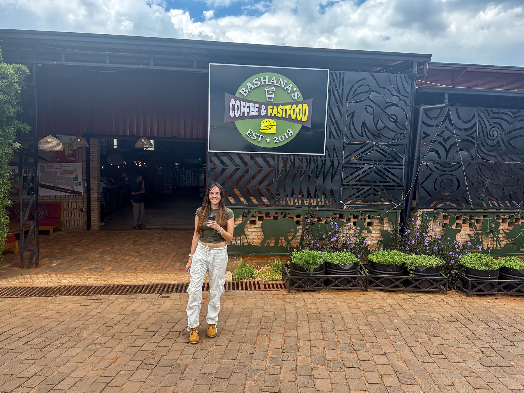 Ella McKendrick standing outside Bashana's Coffee and Fastfood at Journey from Akagera National Park to Kigali, Rwanda