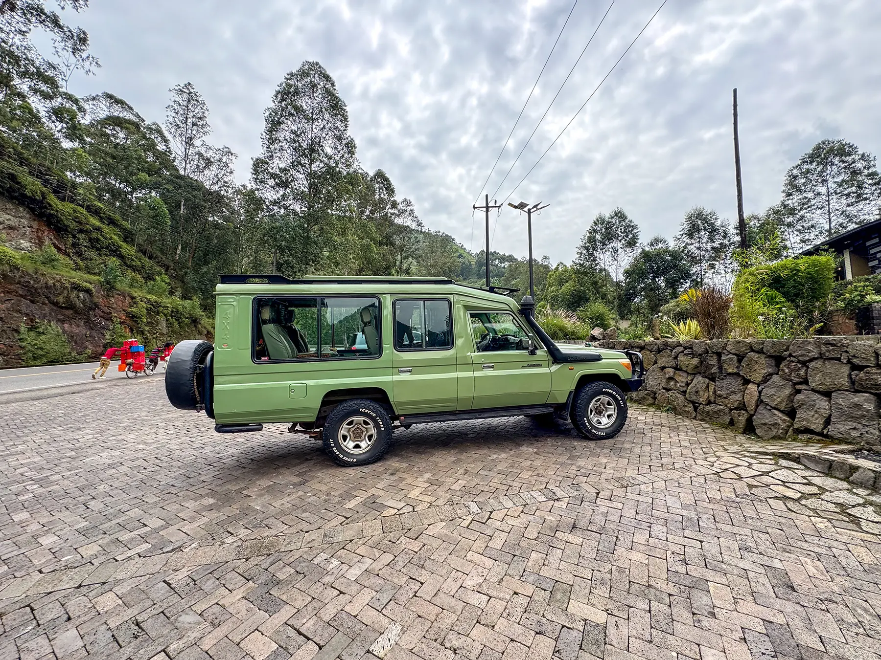 Green Toyota Land Cruiser parked on cobbled forecourt at Musanze in Volcanoes National Park, Rwanda