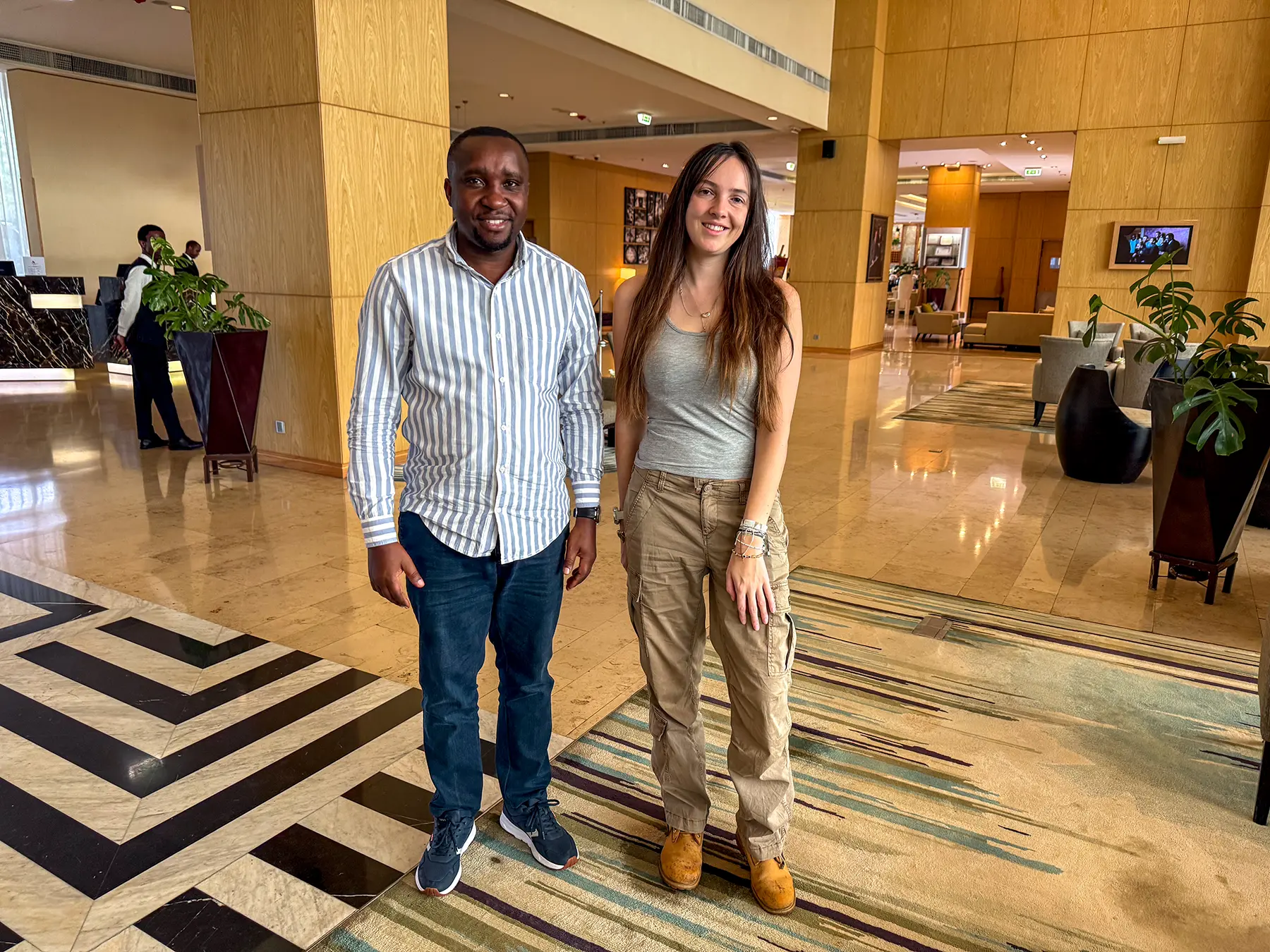 Ella McKendrick and a local tour operator standing in a marble hotel lobby at a hotel in Kigali, Rwanda