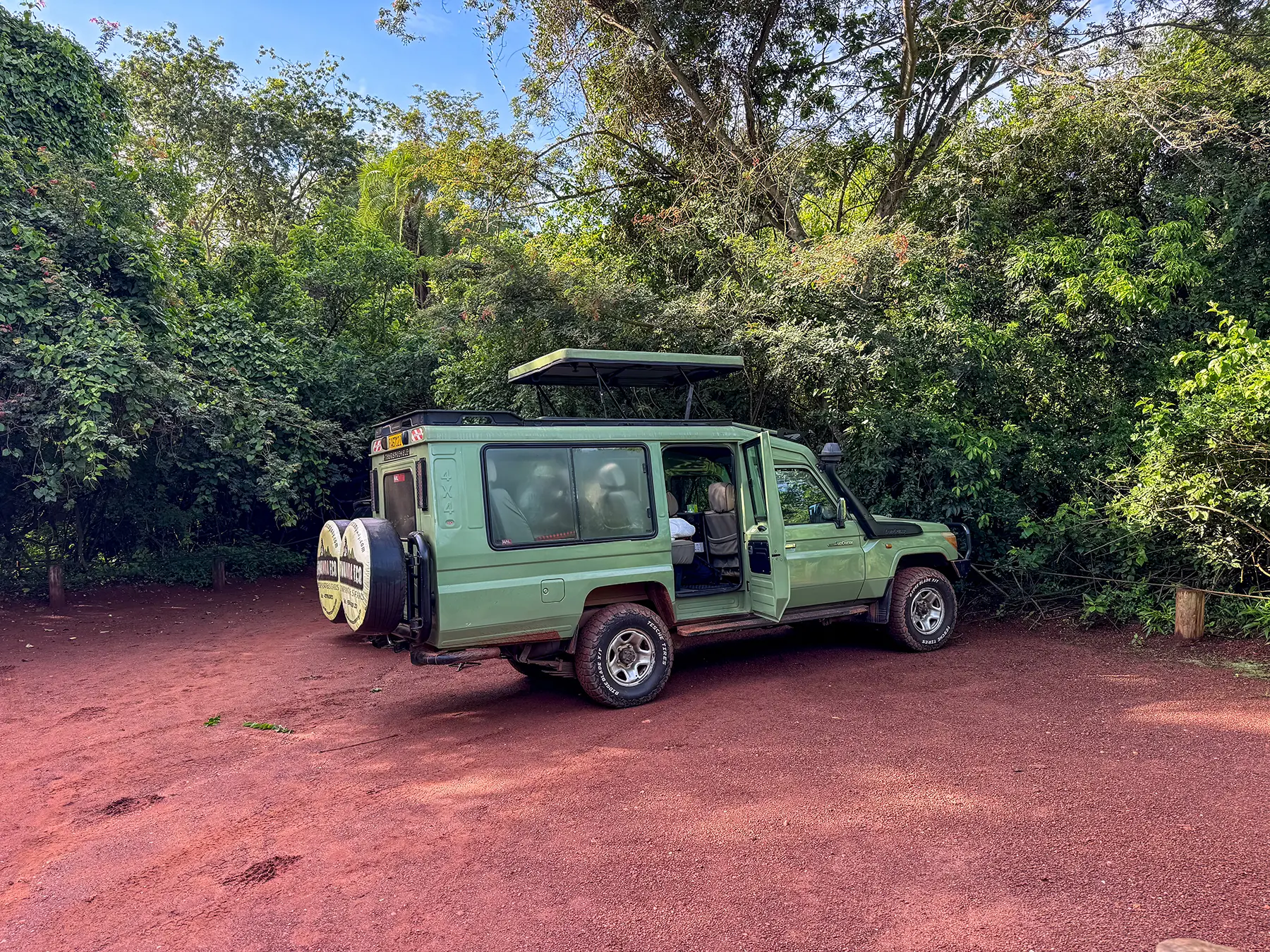 Green Toyota Land Cruiser safari vehicle in a forest clearing at a safari vehicle parking area, Rwanda