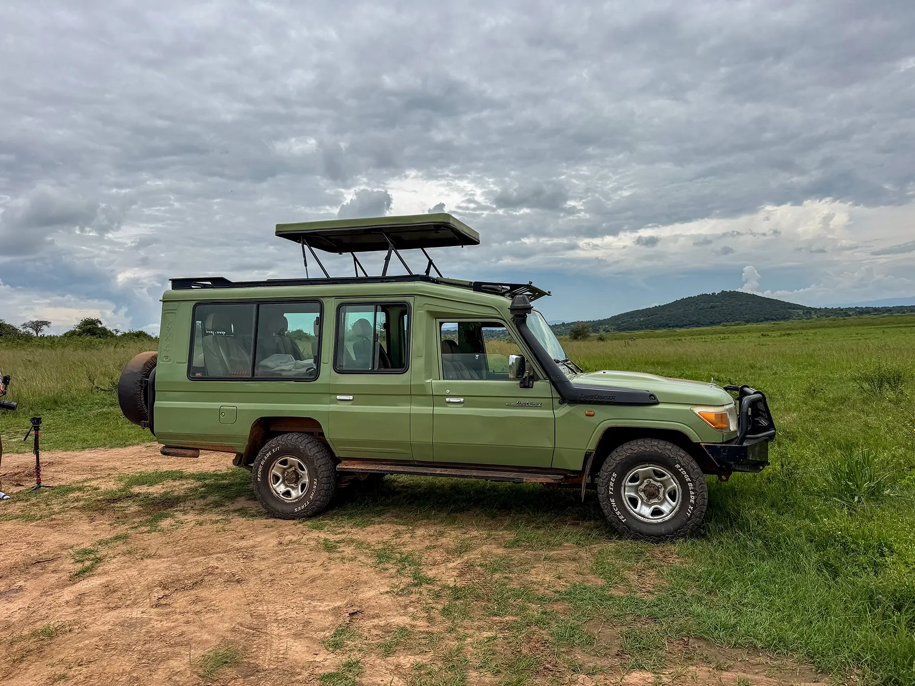 Green Toyota Land Cruiser safari vehicle parked on open savanna at Akagera National Park, Rwanda