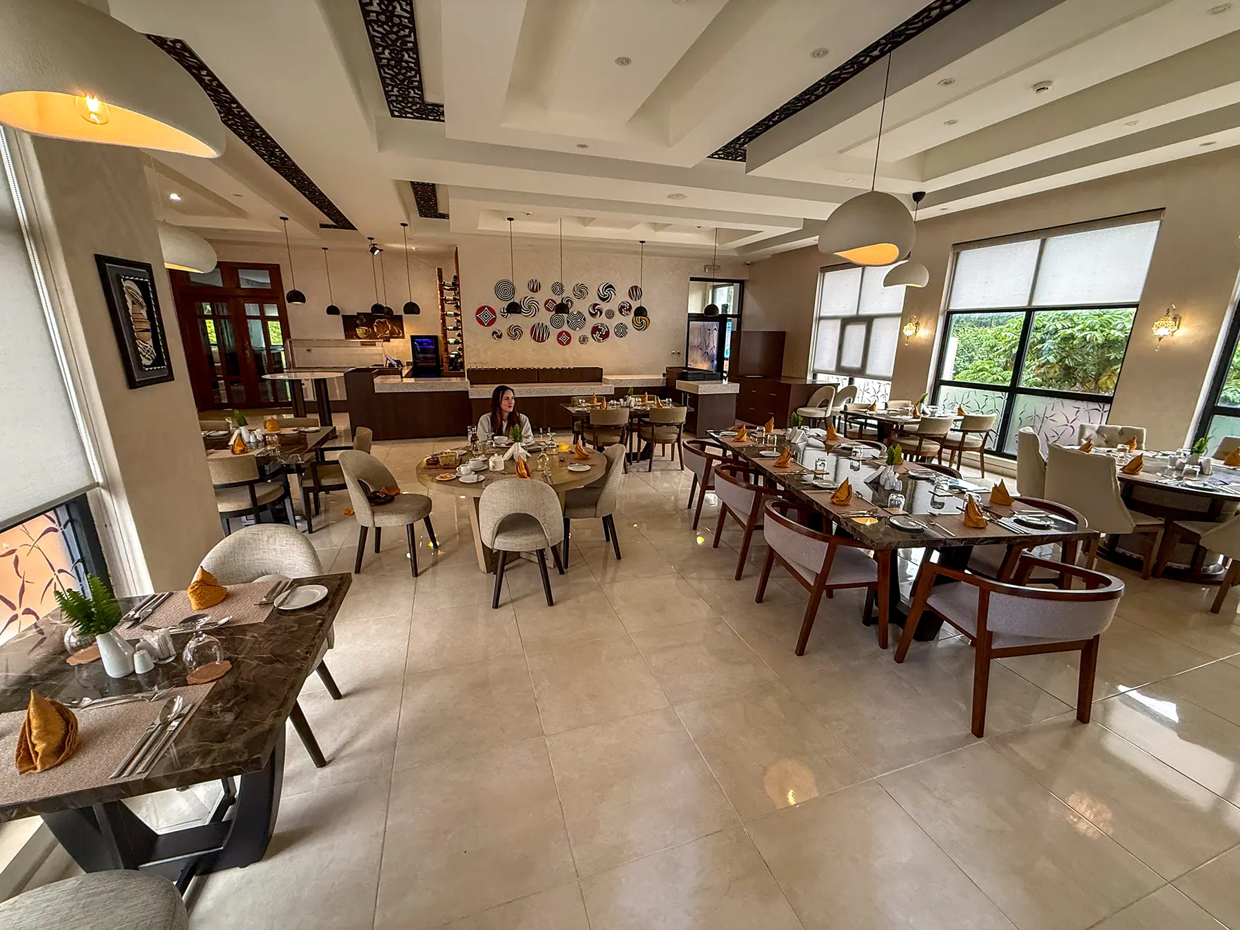 Bright dining room with set tables and decorative plate wall at Virunga Inn in Volcanoes National Park, Rwanda