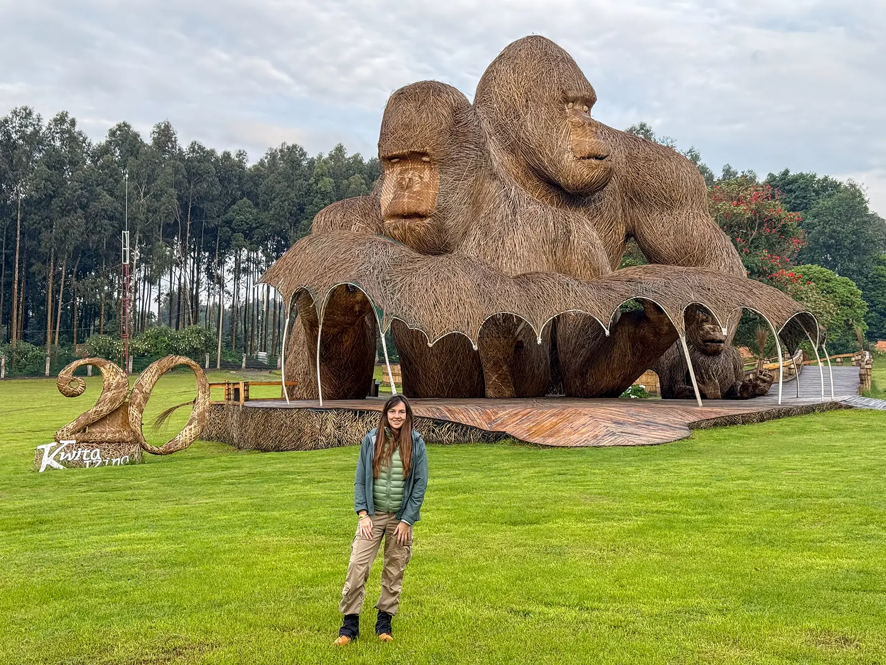 Ella McKendrick standing in front of giant straw gorilla sculptures at Kwita Izina ceremony grounds in Volcanoes National Park, Rwanda