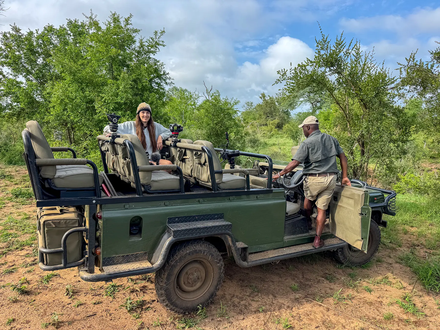 Ella McKendrick and a safari guide in an open safari truck with camera rigs at a bush stop in South Africa