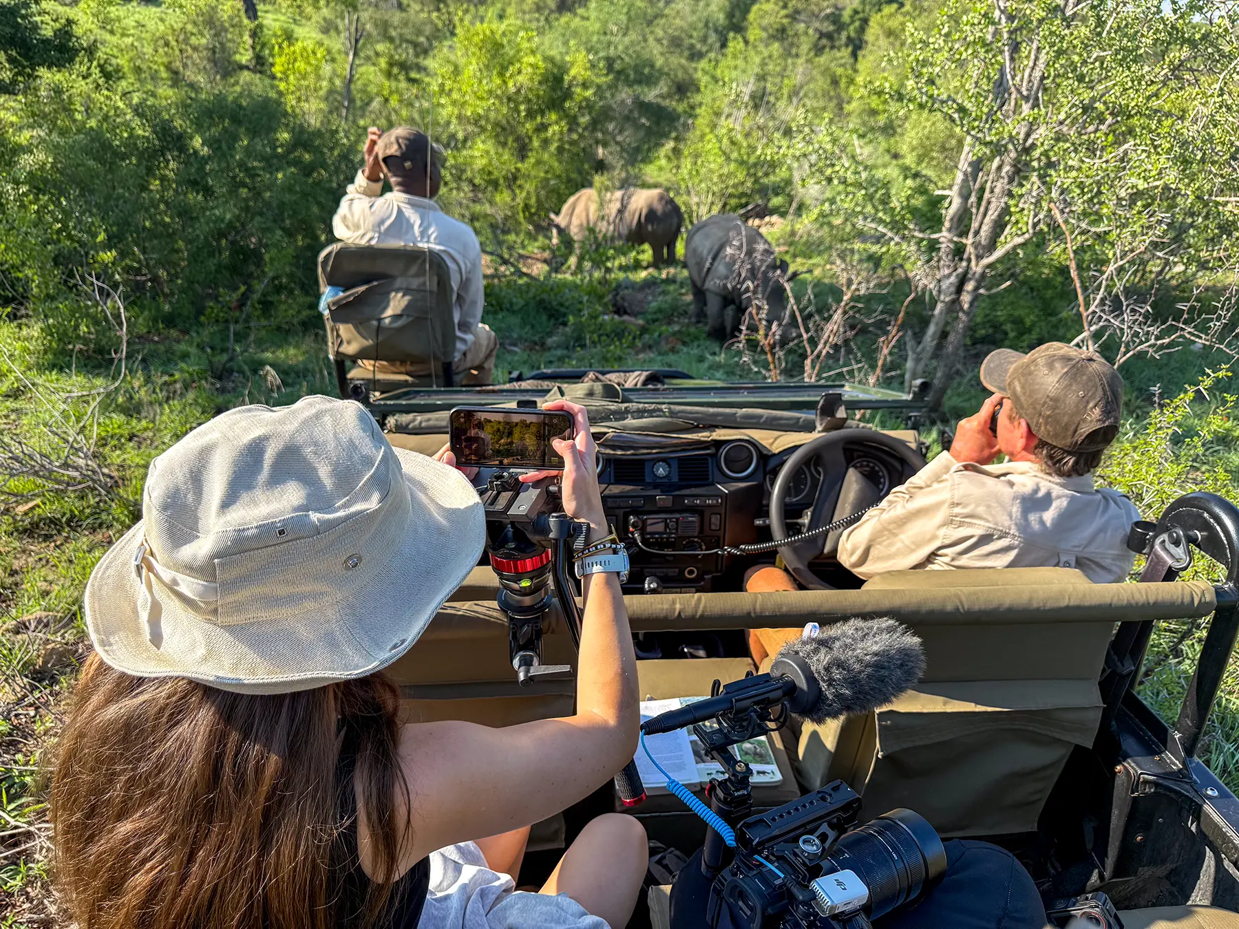 Ella McKendrick photographing two rhinos with a phone from a safari truck on safari in Timbavati Private Nature Reserve, South Africa