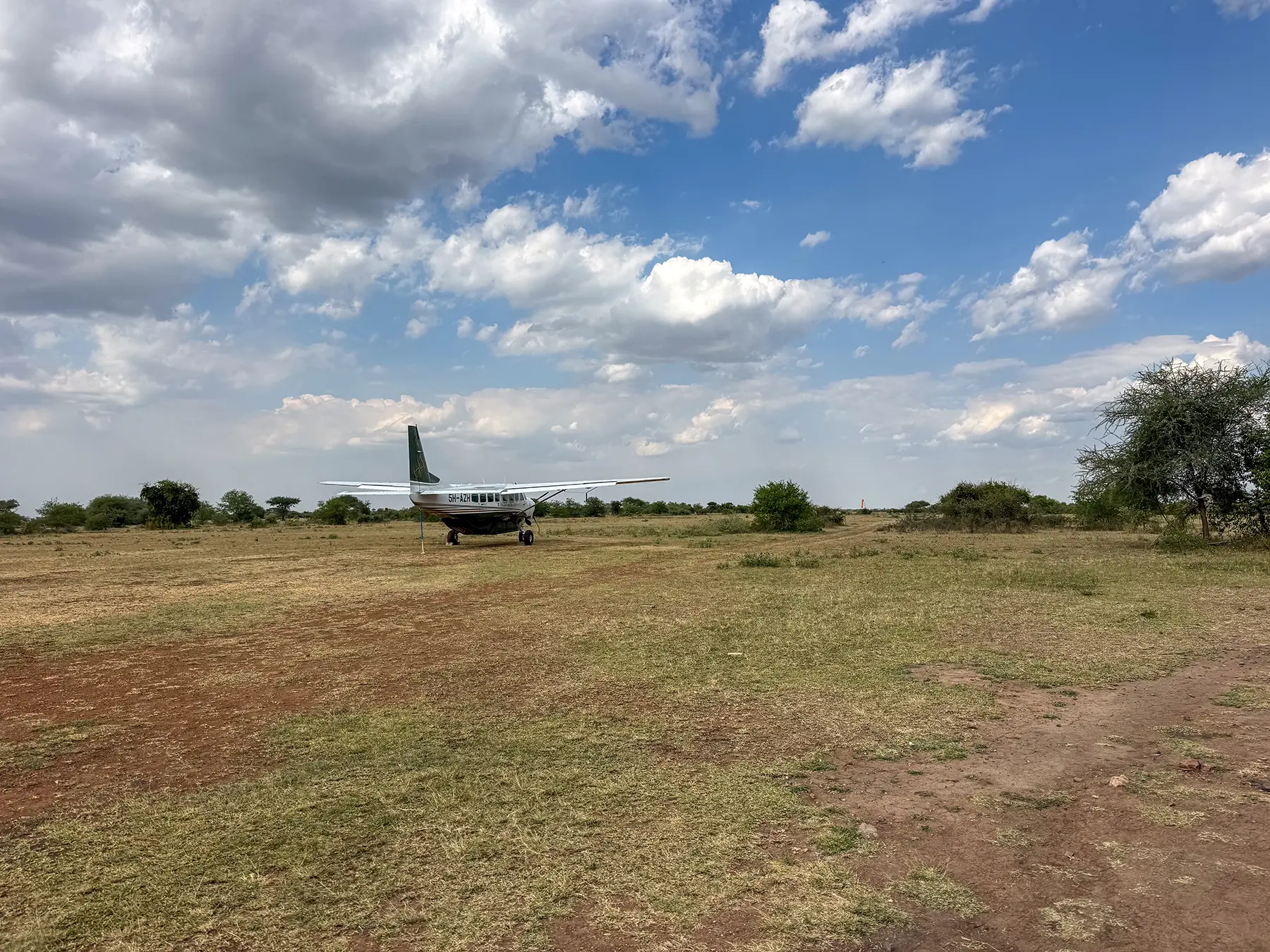 Light aircraft parked on a grass runway with scattered scrub at Grumeti Airstrip, Serengeti, Tanzania