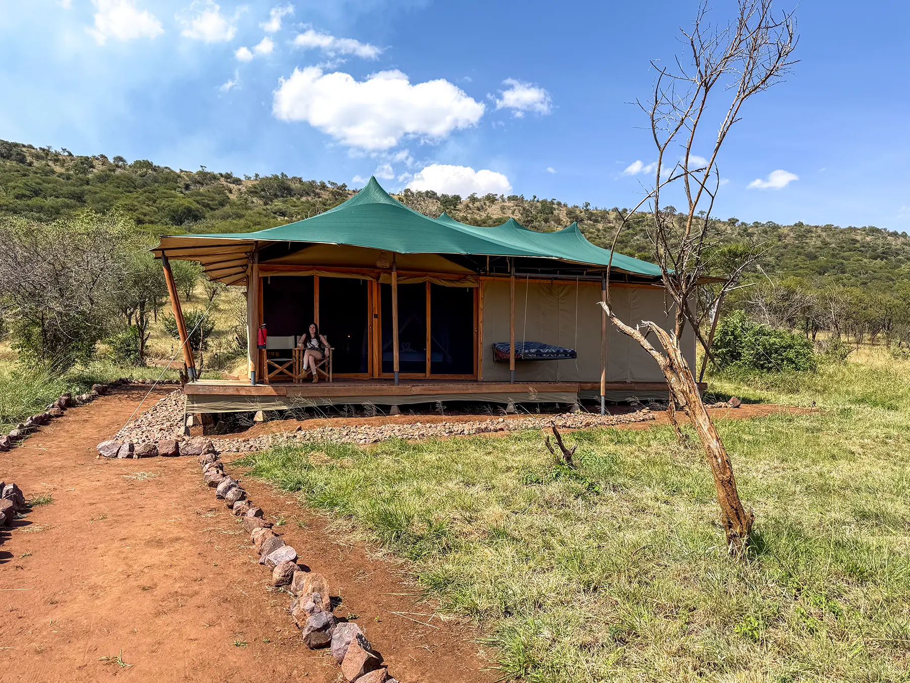 Ella McKendrick on the deck of a canvas-roofed guest room with hillside behind at Safari Haven Serengeti in Serengeti National Park, Tanzania